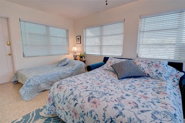 a bedroom with two beds and next to a window