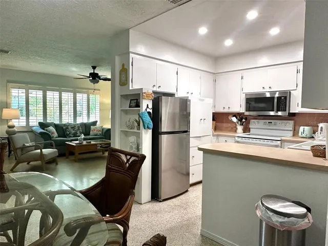 a kitchen with stainless steel appliances a refrigerator a stove a sink dishwasher a dining table and chairs
