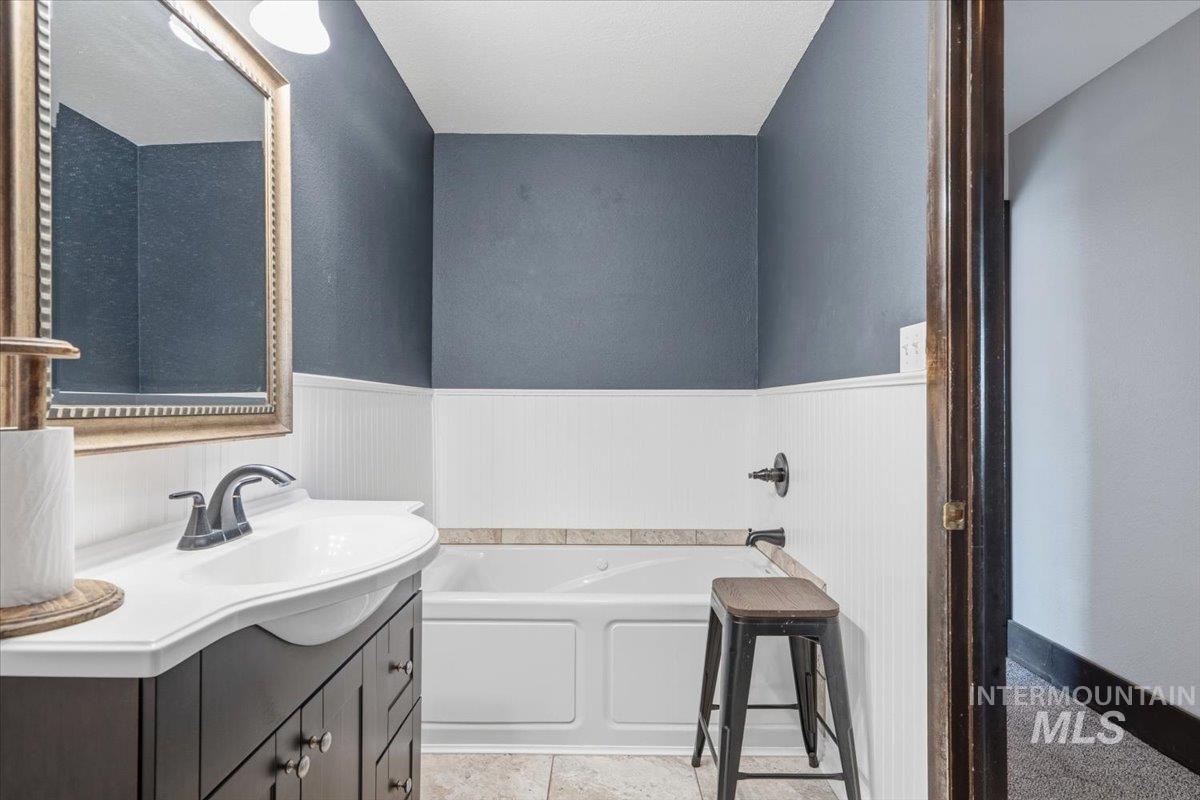 7771 Elmore Road Fruitland, ID 83619 - Photo 12 of 48 Bathroom with vanity, a bath, and wainscoting