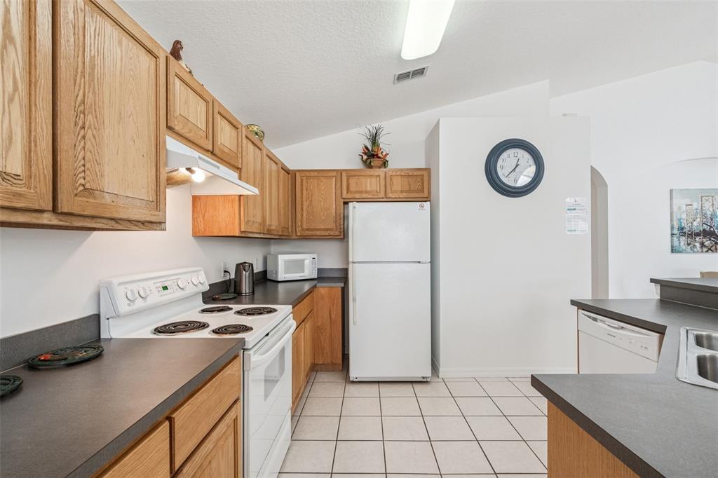 1202 Winding Cypress Court Kissimmee, FL 34746 - Photo 12 of 41 a kitchen with a refrigerator a stove top oven a sink and cabinets