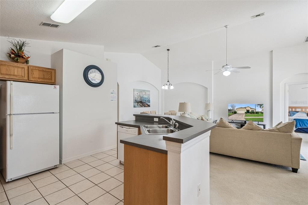 1202 Winding Cypress Court Kissimmee, FL 34746 - Photo 10 of 41 a kitchen with a refrigerator a stove top oven a clock and a window