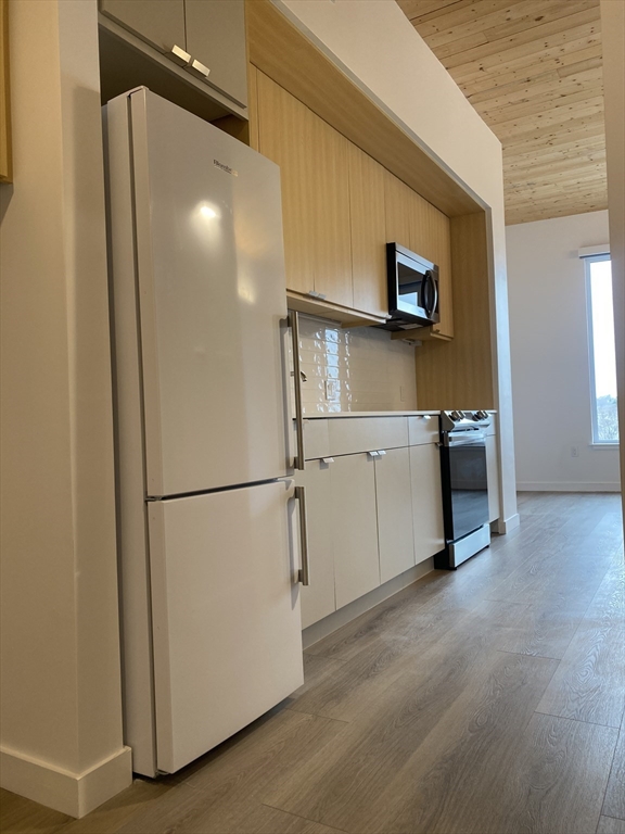 154 Broadway, Unit 507 Somerville, MA 02145 - Photo 15 of 31 a view of a kitchen with a refrigerator and a microwave