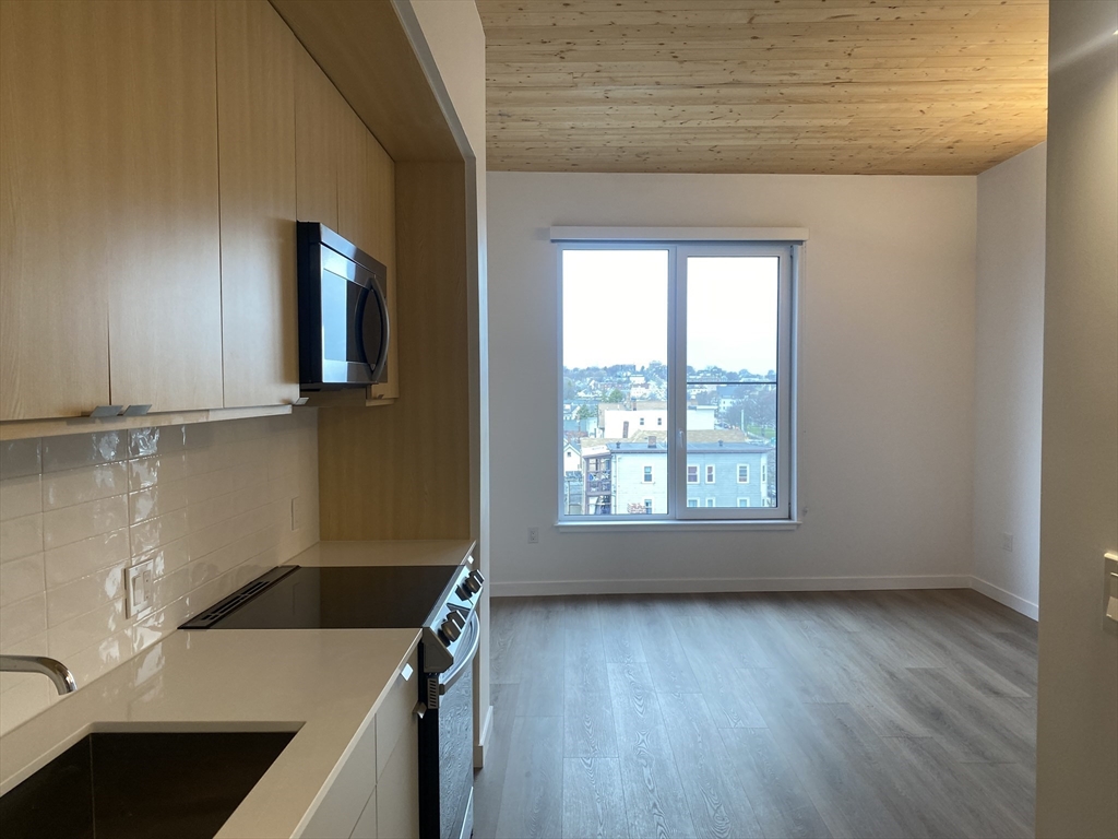 154 Broadway, Unit 507 Somerville, MA 02145 - Photo 17 of 31 a view of a kitchen with wooden floor and electronic appliances