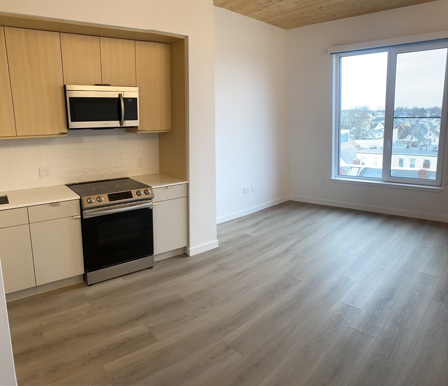 154 Broadway, Unit 507 Somerville, MA 02145 - Photo 19 of 31 a kitchen with stainless steel appliances a stove a microwave and white cabinets