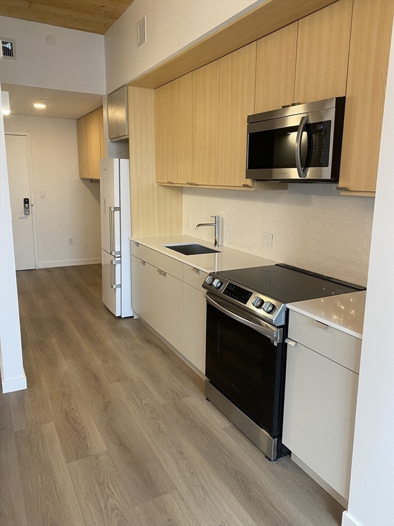 154 Broadway, Unit 507 Somerville, MA 02145 - Photo 2 of 31 a kitchen with stainless steel appliances granite countertop a stove a microwave and a refrigerator