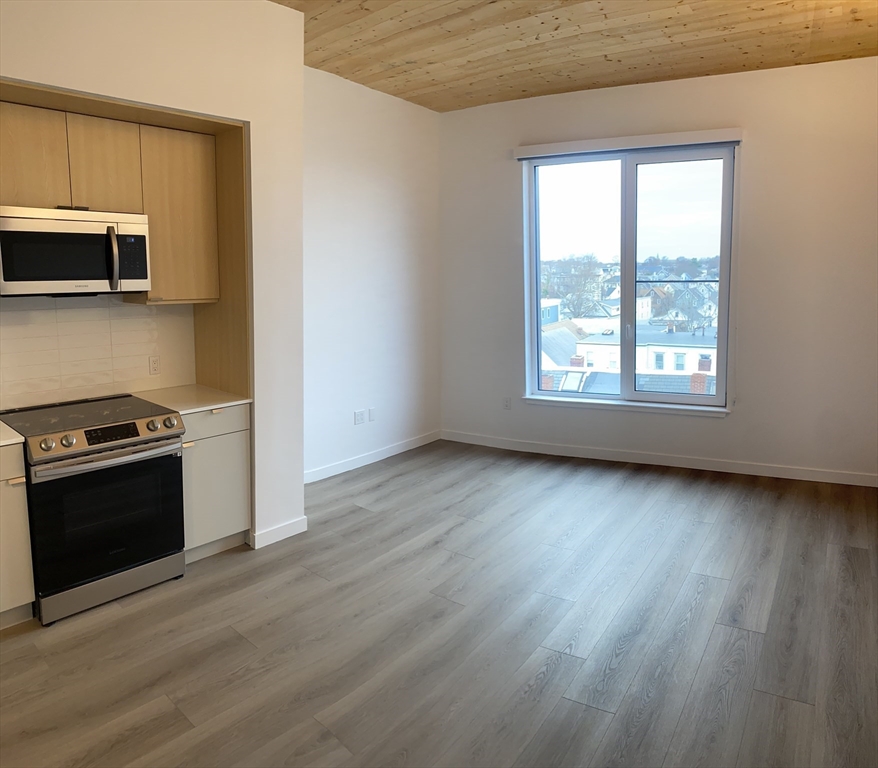 154 Broadway, Unit 507 Somerville, MA 02145 - Photo 22 of 31 a view of a kitchen with a sink wooden floor and a window