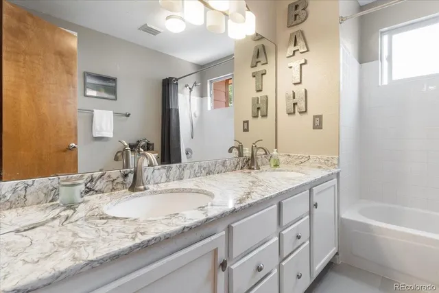 a bathroom with a granite countertop sink double vanity and a mirror
