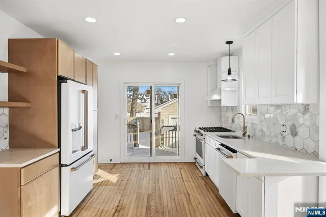 a kitchen with stainless steel appliances a refrigerator a sink and wooden floors