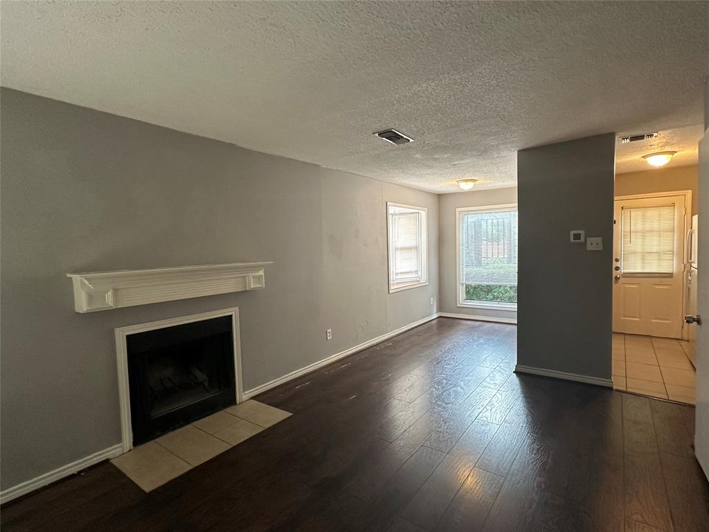 1221 Abrams Road, Unit 109 Dallas, TX 75214 - Photo 2 of 10 Fireplace with a white mantel, wood-finish flooring, and neutral wall paint