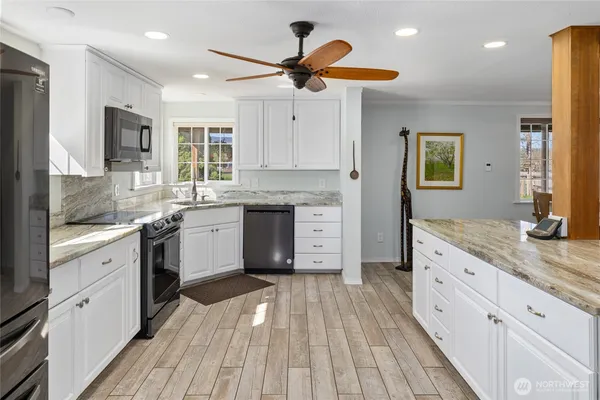 a kitchen with granite countertop a sink cabinets stainless steel appliances and a counter top space
