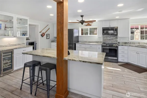 a kitchen with stainless steel appliances granite countertop a stove top oven a sink dishwasher and a refrigerator with wooden floor