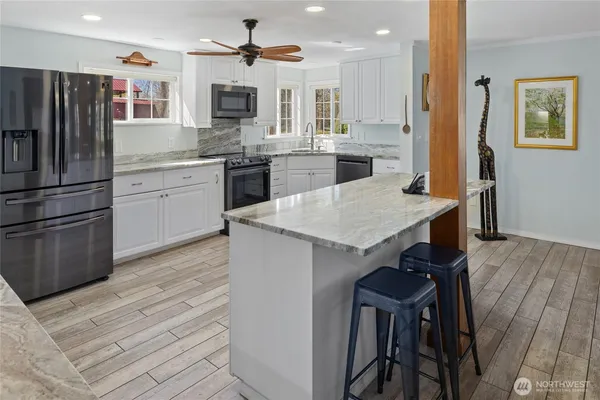 a kitchen with a refrigerator a sink dishwasher a stove and a dining table with wooden floor