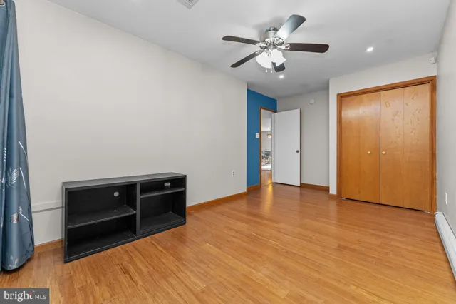 an empty room with wooden floor and ceiling fan