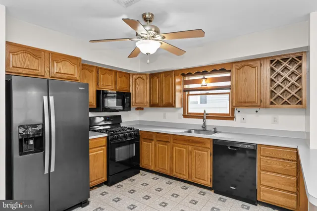 a kitchen with stainless steel appliances a sink a stove a refrigerator cabinets and a window