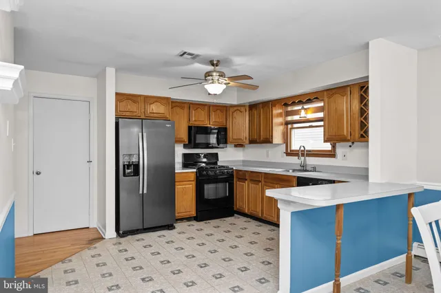 a kitchen with stainless steel appliances granite countertop a sink a stove a refrigerator cabinets and a dining table