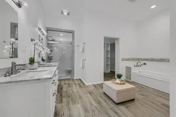 a bathroom with a sink double vanity granite tub shower and a mirror