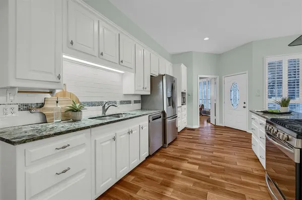a large kitchen with stainless steel appliances granite countertop a lot of counter space and wooden floors