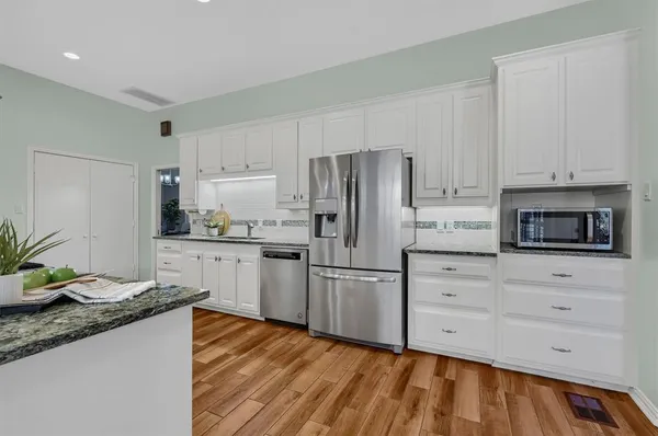 a kitchen with granite countertop white cabinets and stainless steel appliances