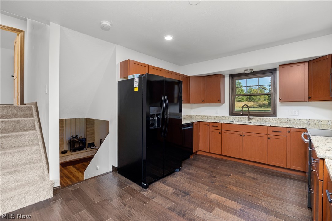 6760 Mason Road Berlin Heights, OH 44814 - Photo 10 of 49 Kitchen featuring black appliances, light stone countertops, brown cabinetry, dark wood finished floors, and recessed lighting
