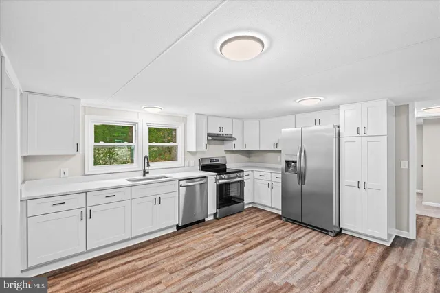 a kitchen with stainless steel appliances granite countertop a stove and white cabinets