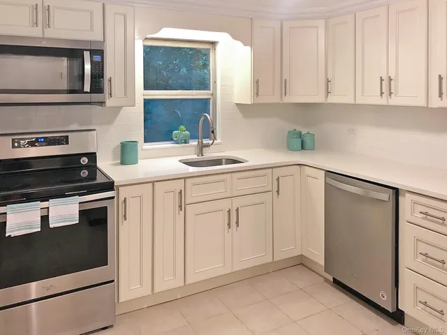 a kitchen with white cabinets and sink