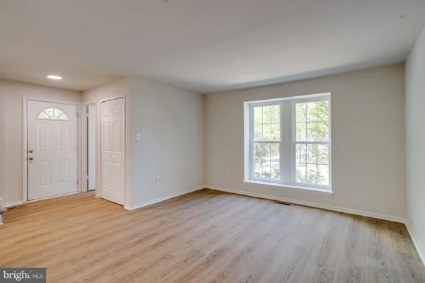 a view of an empty room with wooden floor and window
