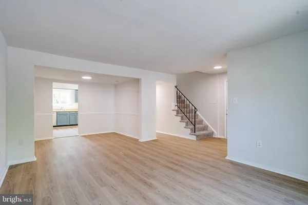 a view of an empty room with wooden floor and stairs