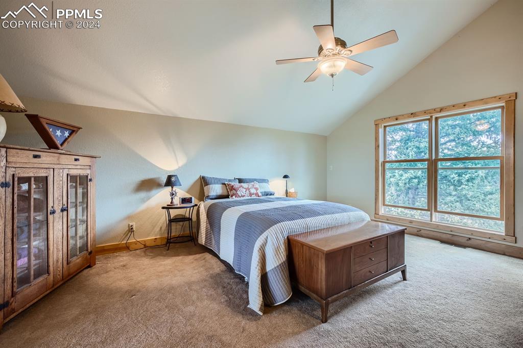 182 Joshua Road Divide, CO 80814 - Photo 21 of 41 a spacious bedroom with a large bed and a chandelier