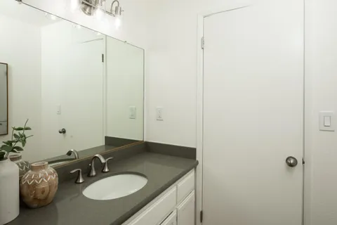 a bathroom with a granite countertop sink and a mirror