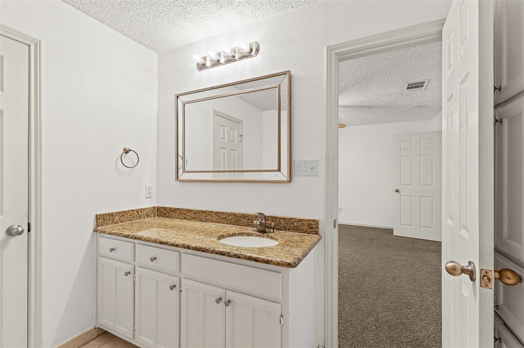 1013 Mockingbird Drive Grapevine, TX 76051 - Photo 19 of 26 a bathroom with a granite countertop sink and a mirror