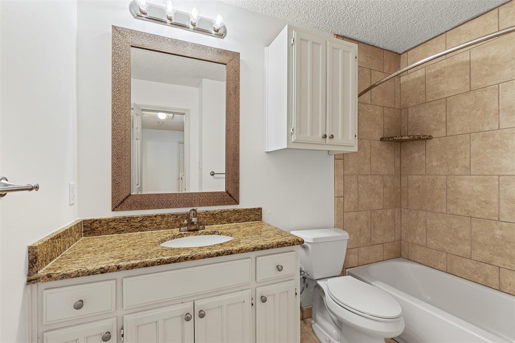 1013 Mockingbird Drive Grapevine, TX 76051 - Photo 21 of 26 a bathroom with a granite countertop sink a toilet and shower