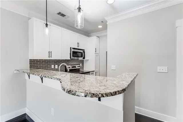 a kitchen with granite countertop a sink stainless steel appliances and white cabinets