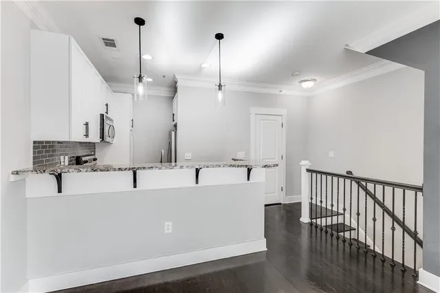 a large white kitchen with kitchen island a sink stainless steel appliances and a chandelier