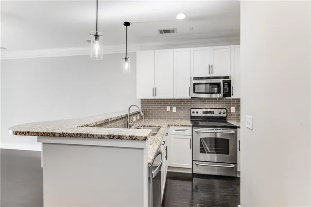 a kitchen with stainless steel appliances granite countertop a sink stove and microwave