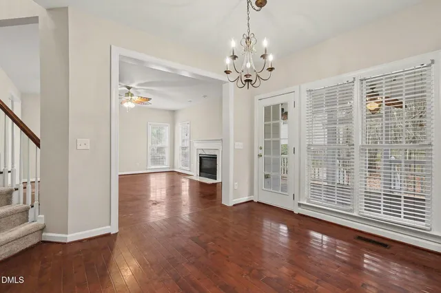 a view of a livingroom with wooden floor a ceiling fan and windows