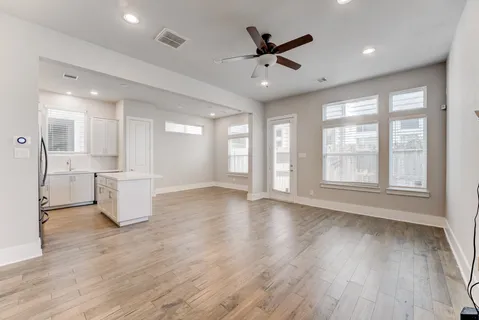 a view of an empty room with a window and wooden floor