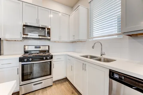 a kitchen with stainless steel appliances granite countertop white cabinets a sink and a stove