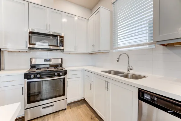 a kitchen with stainless steel appliances granite countertop white cabinets a sink and a stove