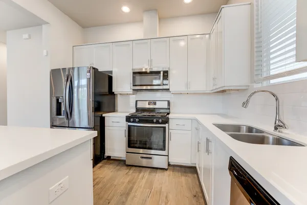 a kitchen with stainless steel appliances a refrigerator sink and microwave