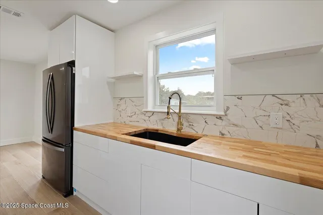 a kitchen with stainless steel appliances granite countertop a sink and a refrigerator