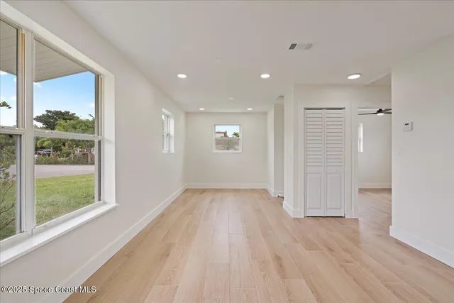 a view of empty room with wooden floor and fan