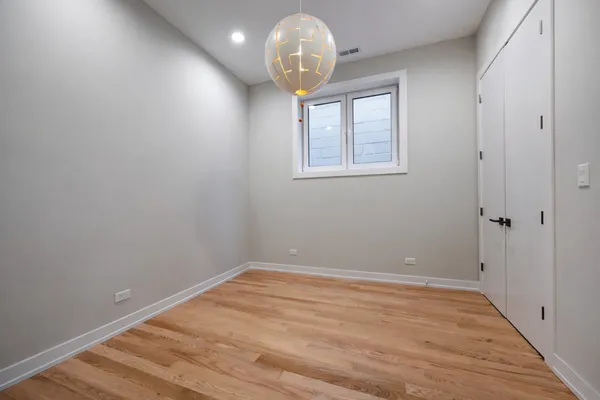 a room with a chandelier fan and wooden floor
