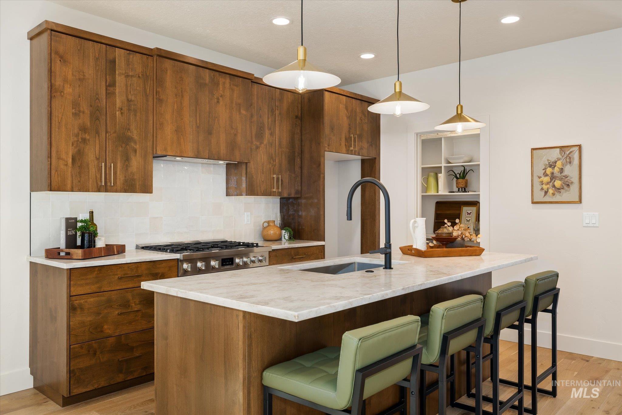5612 West Grover Street Boise, ID 83705 - Photo 15 of 50 Kitchen featuring a breakfast bar, hanging light fixtures, a center island with sink, light wood-style flooring, and backsplash
