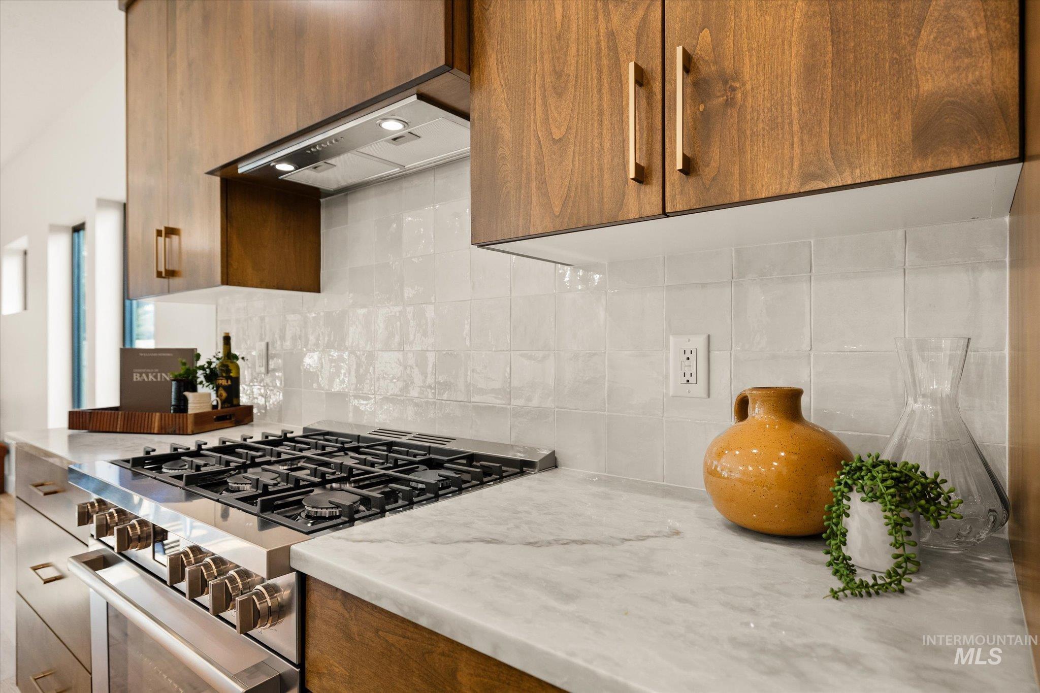 5612 West Grover Street Boise, ID 83705 - Photo 19 of 50 Kitchen featuring gas stove, decorative backsplash, light stone counters, brown cabinets, and ventilation hood