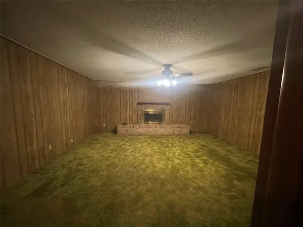 a view of an empty room and chandelier fan