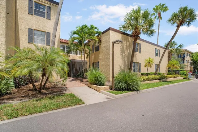 a view of a house with a small yard and palm trees