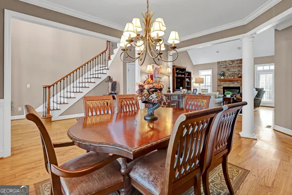 a dining room with furniture wooden floor a rug a potted plant and a chandelier
