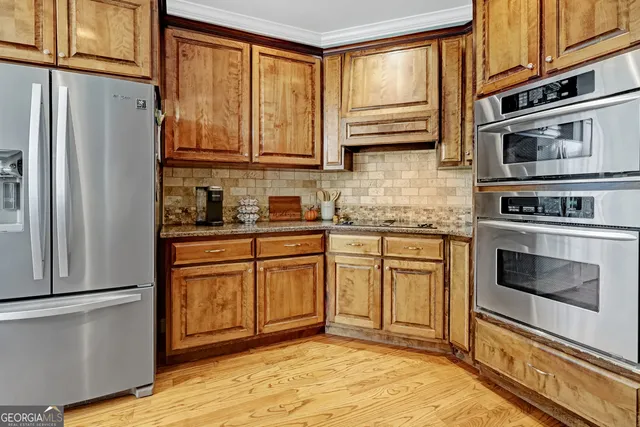 a kitchen with stainless steel appliances granite countertop a refrigerator a stove top oven a sink and dishwasher with wooden floor