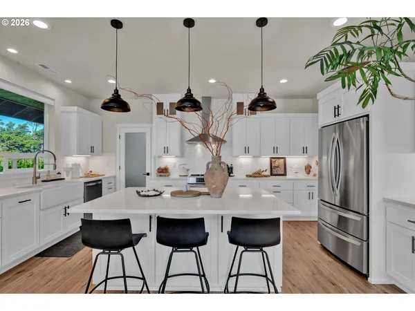 a kitchen with stainless steel appliances kitchen island granite countertop a table chairs and a refrigerator