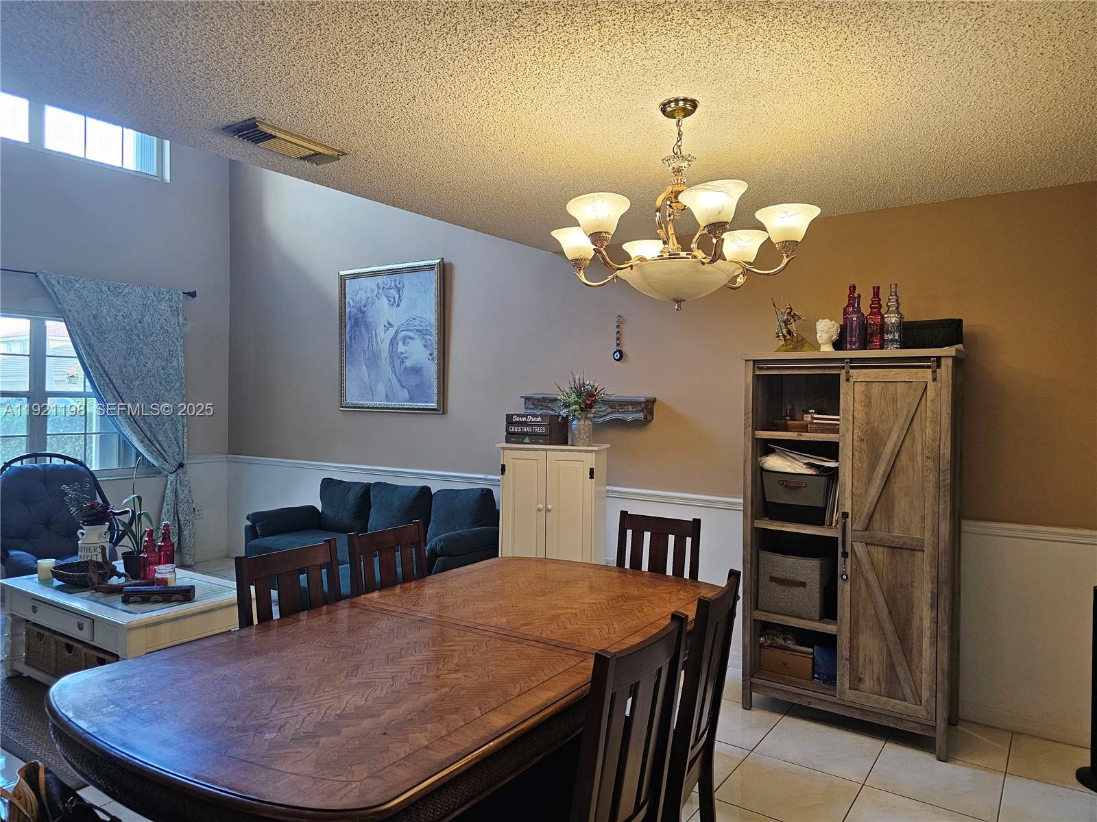 10816 Southwest 75th Street Miami, FL 33173 - Photo 5 of 20 a dining room with wooden floor a chandelier a wooden table and chairs